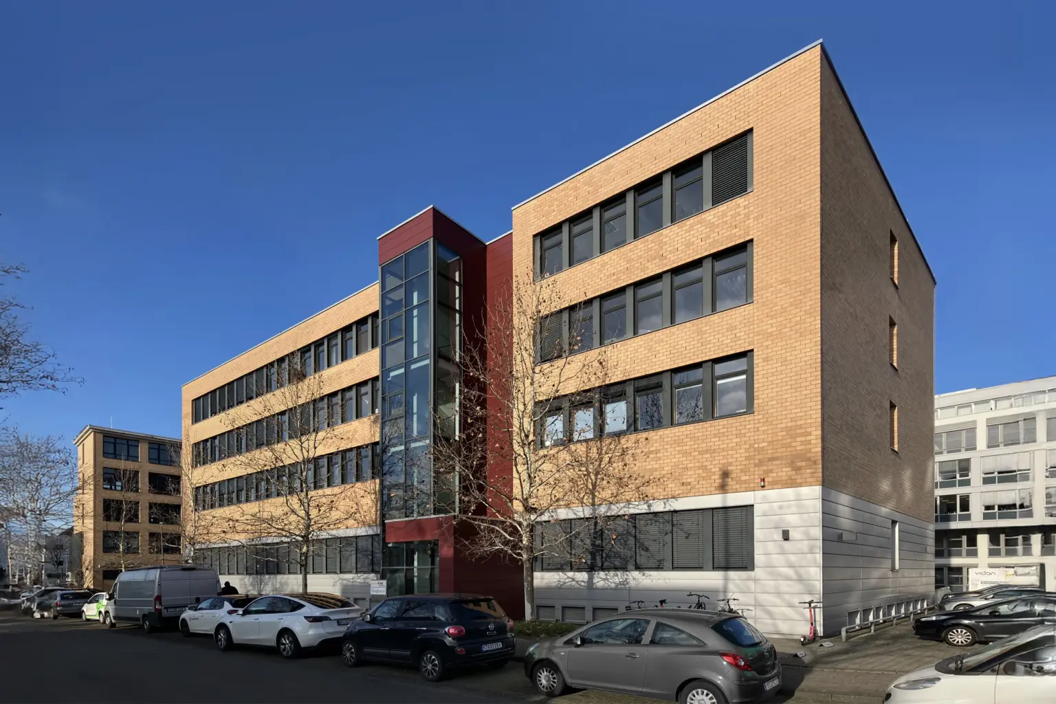 Zeitgenössisches Bürogebäude in Hamburg mit Glasfassade und Parkplätzen.