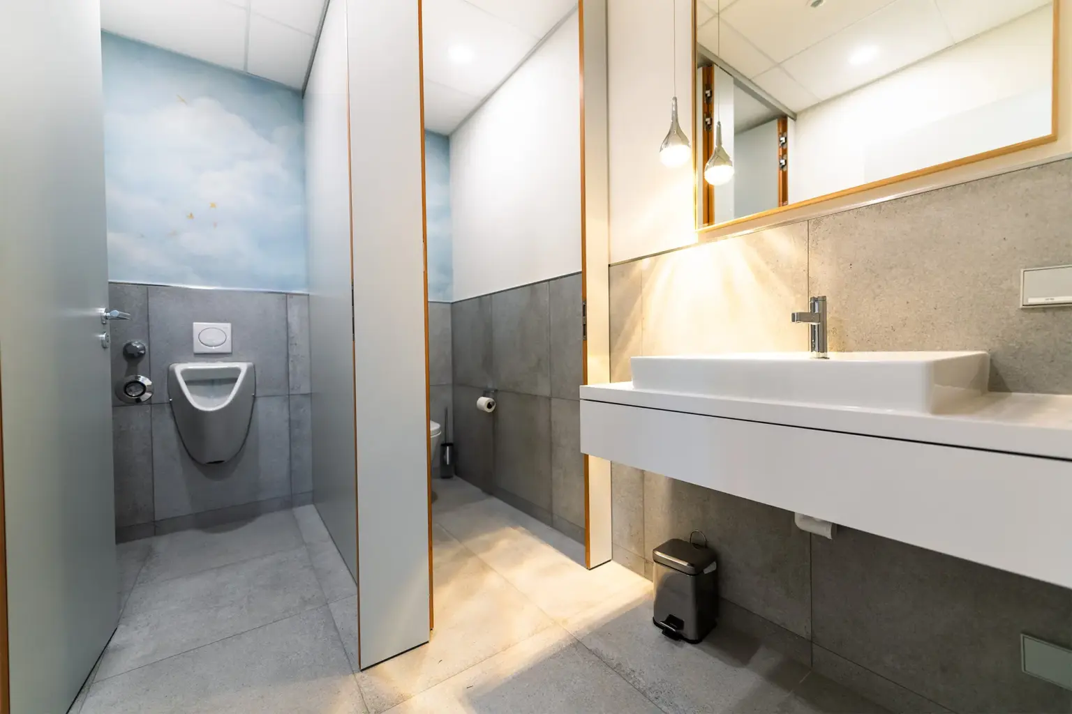 Saubere, moderne öffentliche Toilette mit Waschbecken und Umkleidekabine.