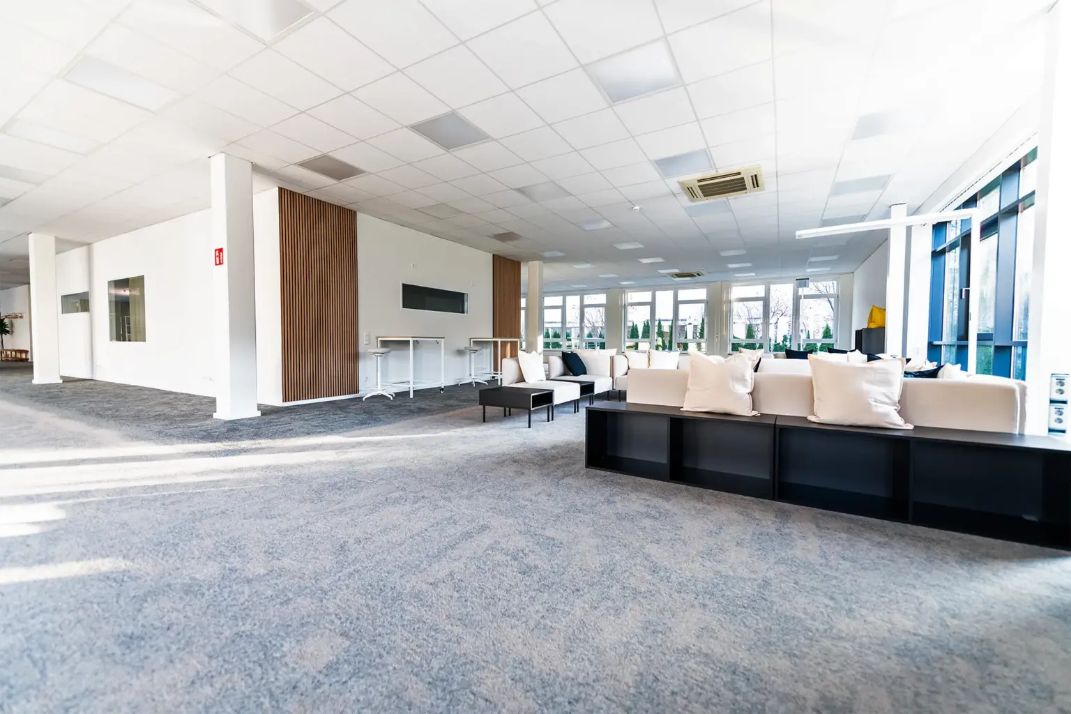 Große, helle Business-Lounge mit komfortablen Sitzgelegenheiten und viel Tageslicht.