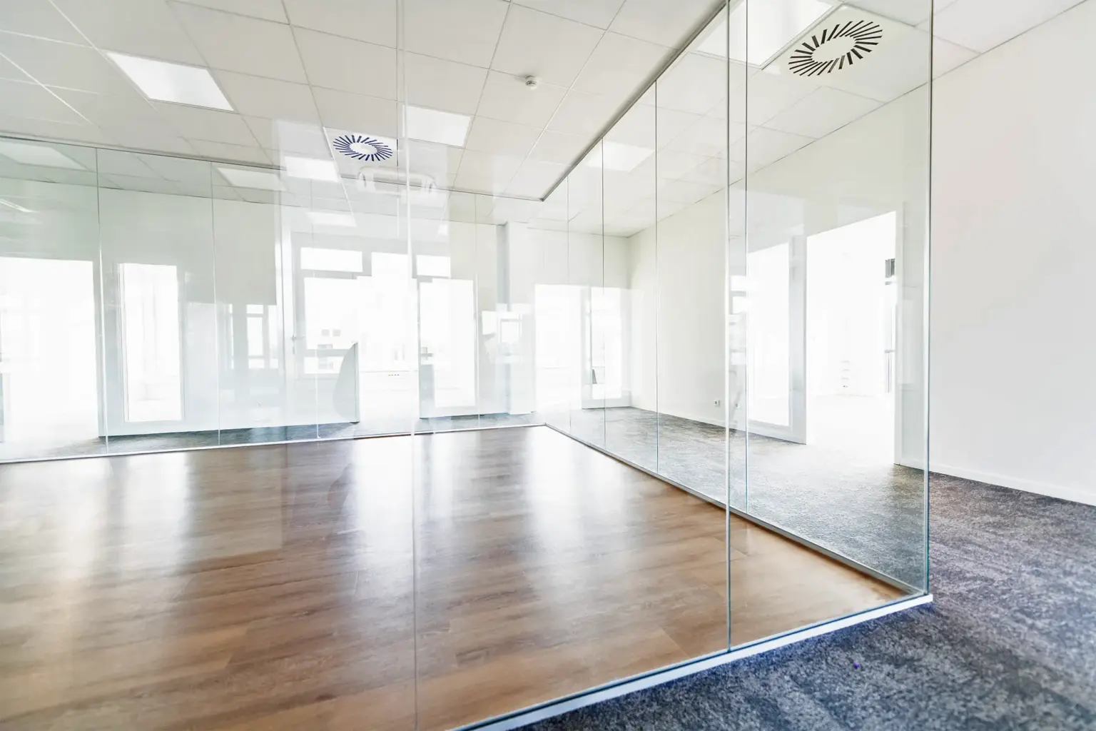 Helles, modernes Büro mit Glaswänden und Holzfußboden.