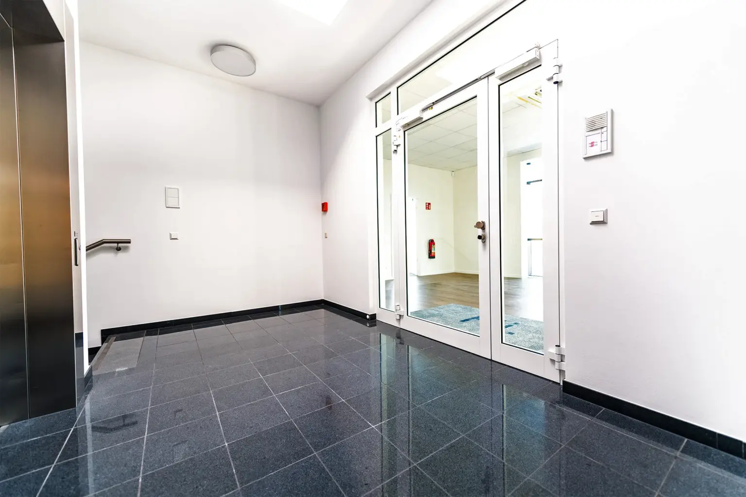 Barrierefreier Eingangsbereich mit Glasfront und Fliesenboden.